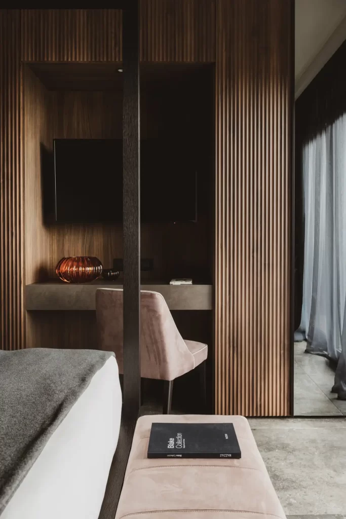 Elegantes Hotelzimmer mit Holzverkleidung, Fernseher, stilvoller Lampe und bequemer Sitzgelegenheit.