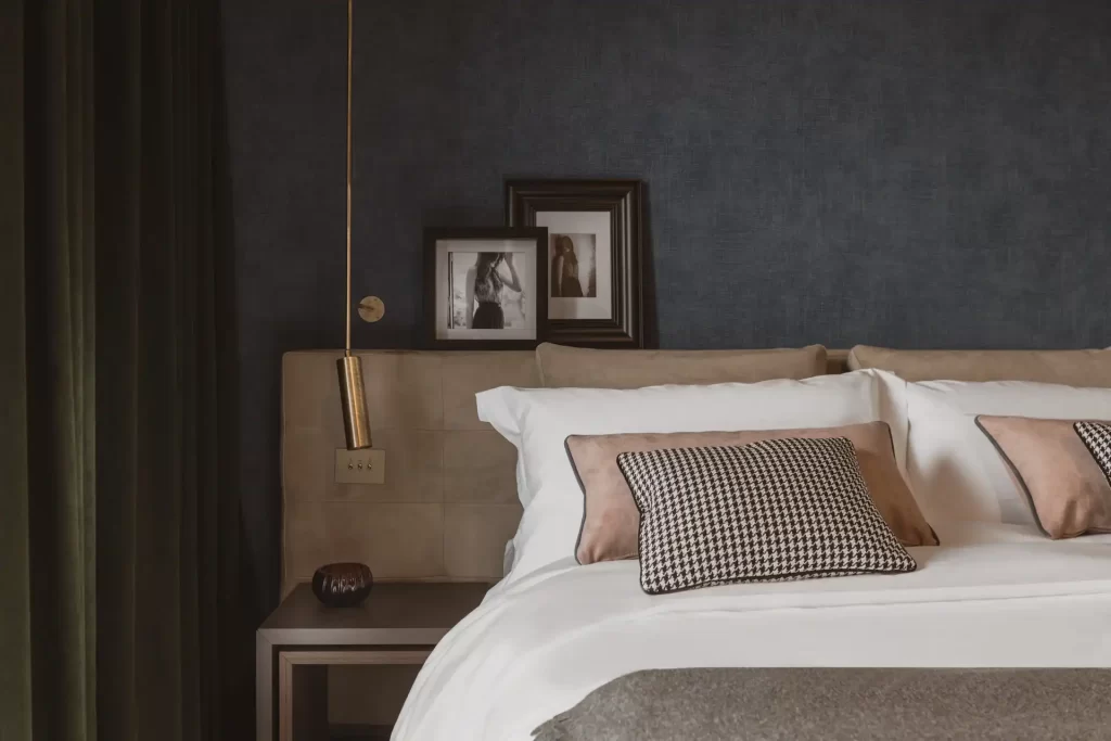Camera da letto moderna con letto elegante, cuscini decorativi e lampada a sospensione.