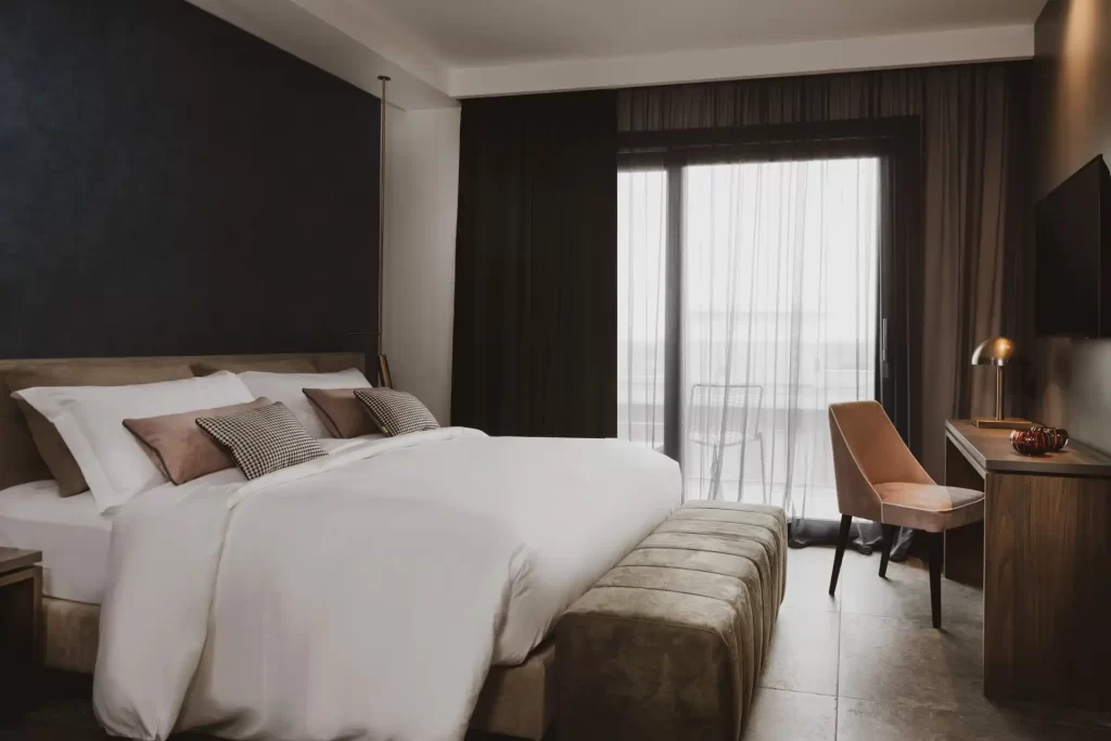 Camera da letto moderna con letto matrimoniale, scrivania e grande vetrata.