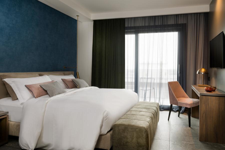 Camera d'albergo moderna con letto matrimoniale, scrivania e grandi finestre.