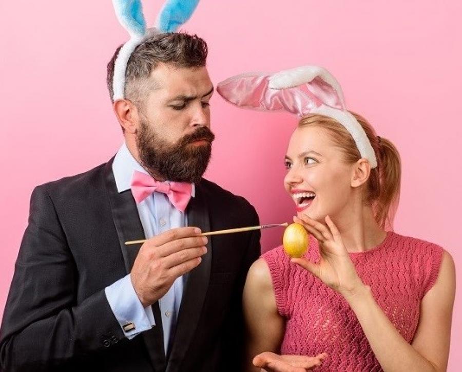 Coppia festosa con orecchie da coniglio dipinge un uovo di Pasqua.