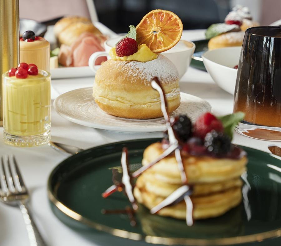 Colazione elegante con pancake ai frutti di bosco, brioche e dolci vari.