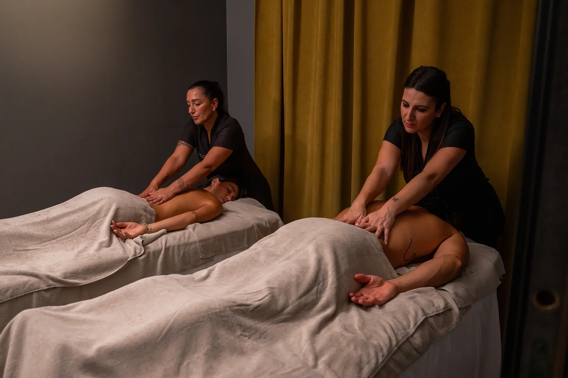 Due terapisti effettuano massaggi rilassanti a coppia in una spa.