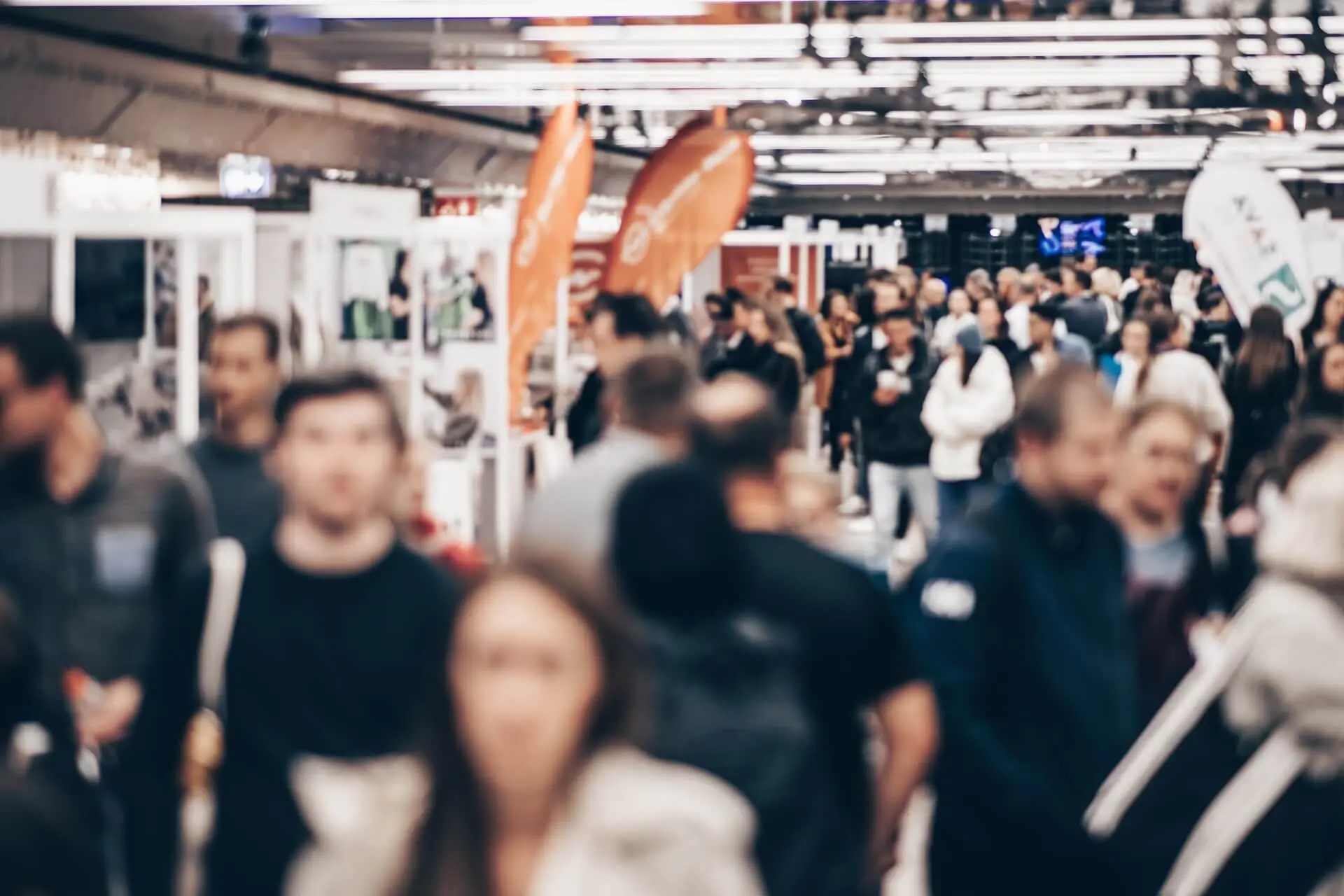 Una folla di persone sfocata in una fiera o esposizione al chiuso.