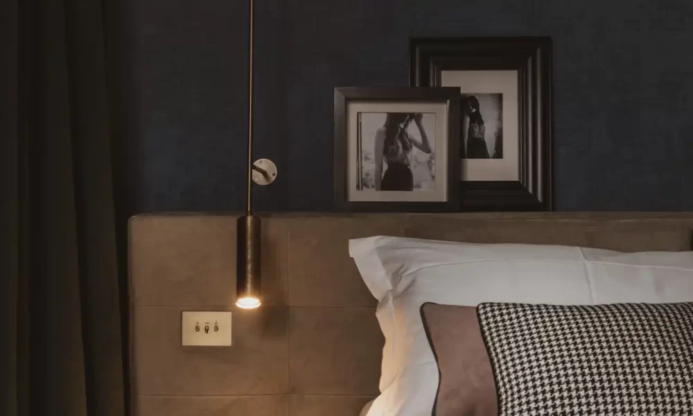 Camera da letto elegante con comodino, lampada a sospensione e decorazioni fotografiche.