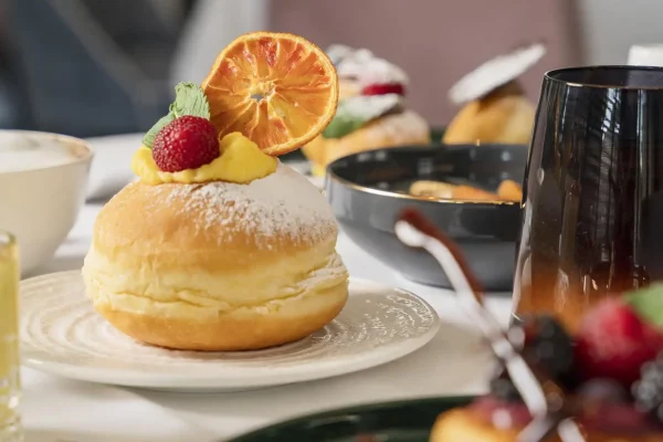 Piatto di dessert elegante con dolci decorati e macedonia su un tavolo in un ambiente raffinato.