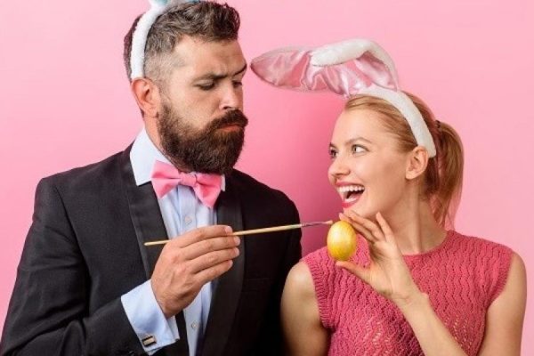 Coppia festosa con orecchie da coniglio dipinge un uovo di Pasqua.