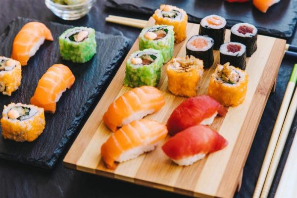 Un assortimento di sushi e nigiri su piatti di ardesia e bambù.